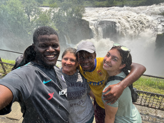 Four people posing in front of a waterfall.